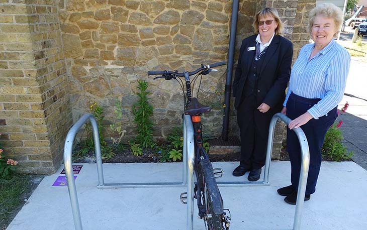Two ladies standing in front of new bike racks that were newly installed.